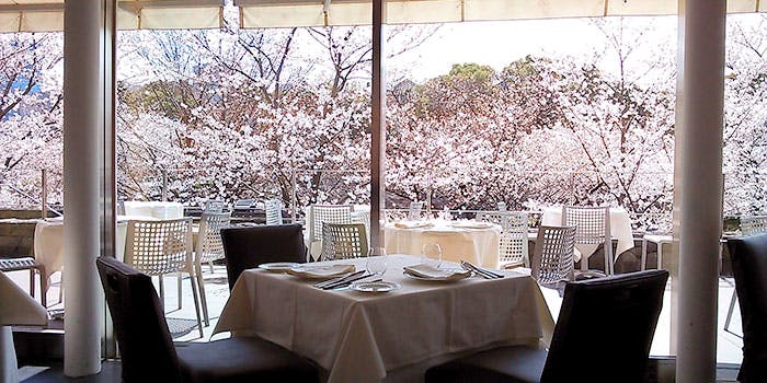 窓際のテーブル席から桜が見える「ラー エ ミクニ」の内観