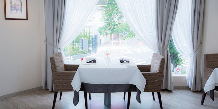 窓際のテーブル席が白で統一された「リストランテツヅキ」の内観