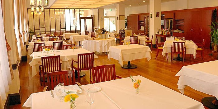 白と木目を基調とした広い店内に、白いテーブルクロスが掛けられた客席がいくつも設置されている。